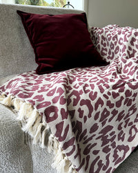 sprei panterprint bordeaux beige op bank met fuweel bordeaux rood kussen