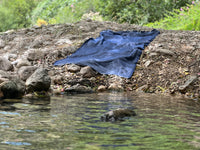 Donkerblauwe hamamdoek op de oever van een beekje