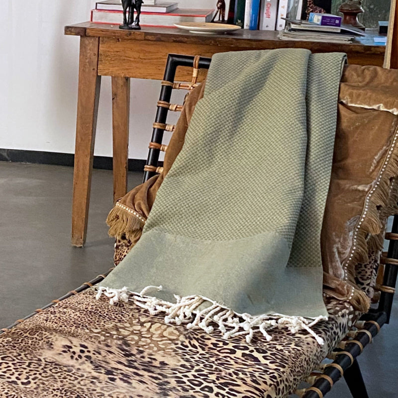 Olijfgroene plaid of grand foulard gevouwen over rugleuning chaise longue