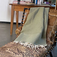 Olijfgroene plaid of grand foulard gevouwen over rugleuning chaise longue